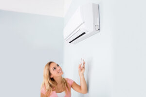 Woman Operating Air Conditioner With Remote